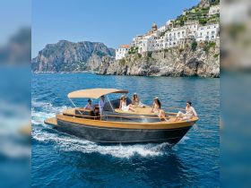 A stylish group enjoys a sunny day aboard a boat, cruising along the stunning Amalfi Coast, perfect for summer adventures and celebrations.