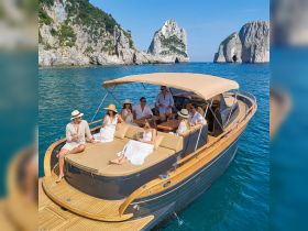 A lively group enjoys a luxurious day on a yacht, celebrating with cocktails against a stunning coastal backdrop — perfect for unforgettable gatherings on the water.