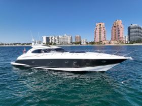 A sleek speedboat glides through clear waters, showcasing its elegant design against a backdrop of coastal buildings — perfect for luxury outings on the water.