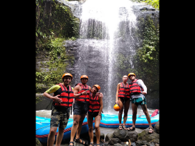 A group of adventurers poses in front of a stunning waterfall, showcasing their excitement for rafting and outdoor exploration.