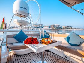 A beautifully arranged table on a yacht featuring fresh roses and a delicious spread, perfect for romantic outings or special celebrations on the water.