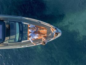 A group of friends relaxes on the deck of a sleek boat, enjoying the sun and clear waters — perfect for a day of fun on the water.