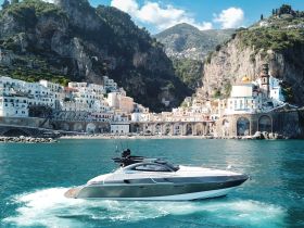 A stunning yacht cruises along the picturesque Amalfi Coast, showcasing the vibrant coastal architecture and crystal-clear waters.