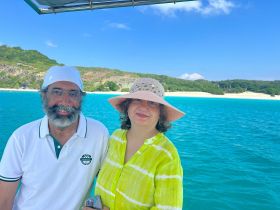 A couple enjoys a picturesque moment on a boat with a stunning beach backdrop, perfect for romantic getaways or scenic tours.