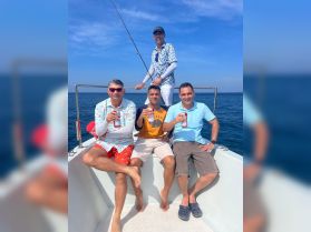 A group of friends enjoys a fishing trip on a boat, celebrating with drinks and laughter under the sunny sky — perfect for a day of adventure on the water.