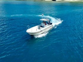A boat speeds through crystal-clear waters, showcasing an exciting day on the water with guests enjoying the ride.