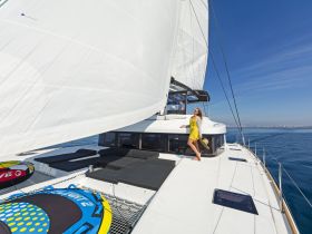 A woman enjoys the sun on the deck of a luxurious yacht while sailing on calm waters, showcasing the perfect blend of relaxation and adventure.