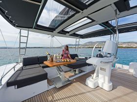 A stylish interior view of a yacht's seating area and helm, featuring a woman enjoying a drink, perfect for relaxing on the water.