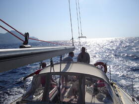 Two individuals enjoy a sunny sailing experience on the open ocean, showcasing the thrill of adventure at sea.