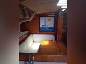 A cozy interior view of a boat's cabin featuring comfortable seating and a decorative painting, perfect for relaxing during a sailing trip.