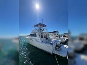 A pristine yacht docked in clear waters under a bright sun, showcasing its sleek design and inviting atmosphere for boating adventures.