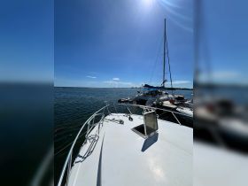 A clear view of the front deck of a yacht docked in calm waters, showcasing the boat's sleek design against a bright blue sky.