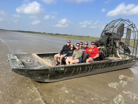 A cheerful group enjoys an airboat tour, showcasing the thrill of exploring marshlands and wildlife in a unique vessel.
