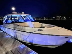 A stunning view of a yacht docked at night, illuminated by blue lights, showcasing its sleek design against a serene waterfront backdrop.
