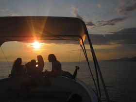 A group of friends enjoys a beautiful sunset aboard a boat, creating a perfect backdrop for memorable moments on the water.