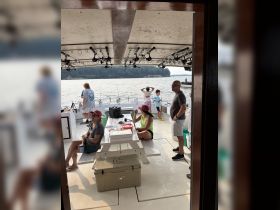 Inside view of a fishing boat with guests enjoying the space, showcasing seating and fishing gear — perfect for a day on the water.