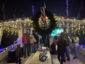 A festive group enjoys a holiday celebration aboard a decorated boat, complete with lights and seasonal cheer, perfect for creating memorable moments on the water.