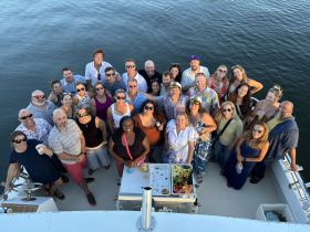 A vibrant group of guests gathers on a boat, enjoying drinks and celebrating together — perfect for memorable outings and gatherings on the water.