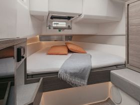Cozy interior cabin of a boat featuring a comfortable bed with decorative pillows, perfect for relaxation during your nautical adventures.