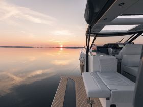 A serene sunset view from the deck of a luxury boat, showcasing the tranquil waters and elegant design — perfect for evening cruises.