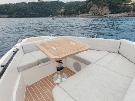 A cozy interior view of a boat's seating area featuring a stylish table, perfect for dining or relaxing while enjoying the scenic waters.