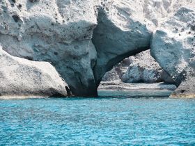 A stunning view of a natural rock arch surrounded by crystal-clear blue waters, showcasing the beauty of coastal landscapes.