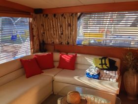Cozy interior of a boat cabin featuring comfortable seating and neatly arranged towels, perfect for relaxing on the water.