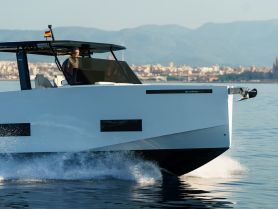A sleek speedboat glides through the water with a captain at the helm, showcasing modern design and performance on the open sea.