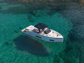 A stunning aerial view of a sleek boat cruising through crystal-clear turquoise waters, showcasing its modern design and elegance.