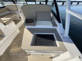 A well-designed interior view of a boat's helm area featuring a grill and seating, perfect for entertaining guests while enjoying time on the water.