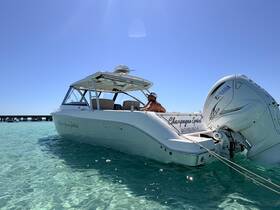 A man relaxes on the deck of the 'Champagne Spirit' boat, surrounded by clear turquoise waters — a perfect setting for a day of adventure on the water.