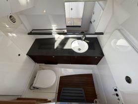 A clean and modern boat bathroom featuring a sink and toilet, showcasing the practical amenities available on board for comfort during trips.