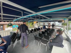 Interior view of a boat cabin with guests preparing for an event, showcasing ample seating and a welcoming atmosphere for gatherings on the water.
