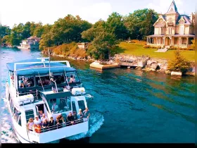 A lively group enjoys a scenic boat ride, with a beautiful historic house in the background, showcasing the perfect blend of adventure and picturesque views.