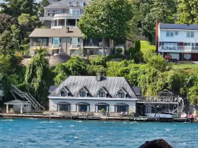 A view of a waterfront property surrounded by lush greenery, showcasing a mix of architectural styles along the shoreline.