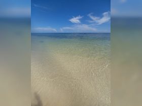 A serene view of calm waters under a clear blue sky, capturing the essence of a tranquil beach day.