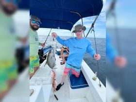 Two anglers proudly display their catch aboard a fishing boat, showcasing a successful day on the water with friends.