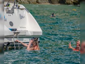 A group of friends enjoys snorkeling and swimming near their boat, capturing the essence of a fun day on the water.