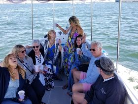 A lively group enjoys a fun celebration aboard a boat, sharing laughs and drinks while soaking up the sun on the water.