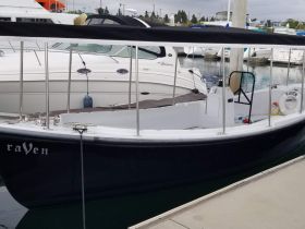 A close-up view of the 'Raven' boat docked at the marina, showcasing its sleek design and structure.