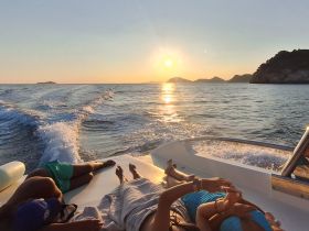 A group relaxes on the deck of a boat while enjoying a stunning sunset over the ocean, creating a perfect backdrop for memorable moments on the water.