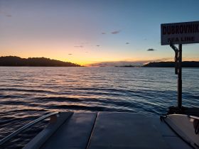 A serene sunset view from the deck of a boat named 'Dubrovnik Sea Line,' showcasing tranquil waters and a distant shoreline, perfect for evening cruises.