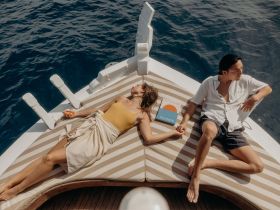 A couple enjoys a relaxing moment on the deck of a boat, soaking up the sun and the ocean views — perfect for romantic getaways or leisurely days on the water.