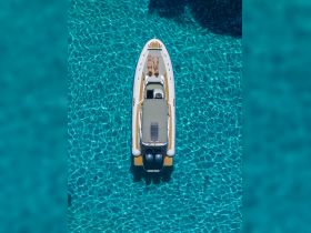 A couple relaxes on the deck of a boat, soaking up the sun in crystal-clear turquoise waters — an idyllic scene for a summer getaway.
