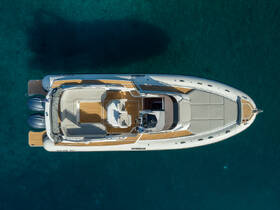 A stunning aerial view of a sleek speedboat anchored in crystal-clear waters, showcasing its elegant design and spacious deck — perfect for a day on the water.