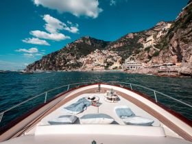 A stunning view from the bow of a yacht cruising along the Amalfi Coast, showcasing picturesque cliffs and charming coastal villages.