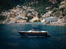 A beautiful boat glides through the waters near the picturesque coastal town of Positano, showcasing the stunning architecture and vibrant colors of the hillside.