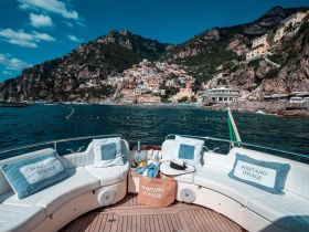 A stunning view of Positano from the deck of a boat, showcasing the vibrant coastal village against a backdrop of lush mountains — perfect for scenic boat trips along the Amalfi Coast.