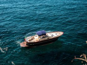 An aerial view of a stylish boat cruising through clear blue waters, showcasing its elegant design and perfect for leisurely outings.