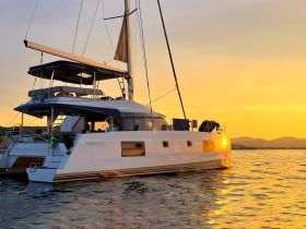 A stunning catamaran anchored at sunset, showcasing its sleek design and tranquil surroundings — perfect for serene evening cruises.